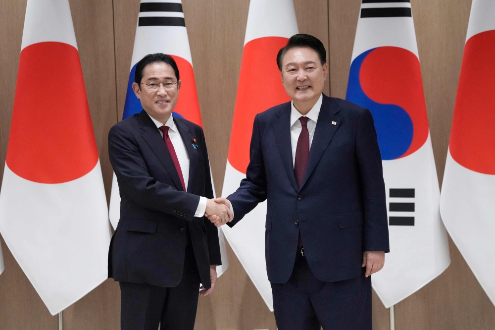 South Korean President Yoon Suk Yeol (R) shakes hands with Japanese Prime Minister Fumio Kishida during a meeting at the Presidential Office in Seoul on May 26, 2024. (Photo by Ahn Young-joon / Pool / AFP)