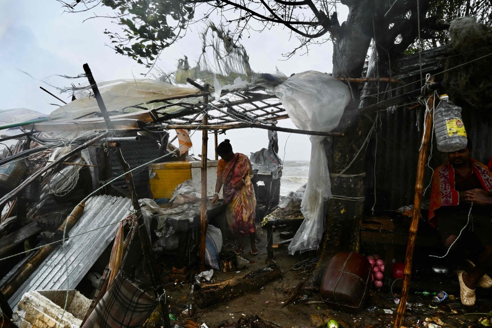 A woman stands next to her damaged house after Cyclone Remal made landfall near a beach in Kuakata on May 27, 2024. (Photo by Munir Uz Zaman / AFP)
