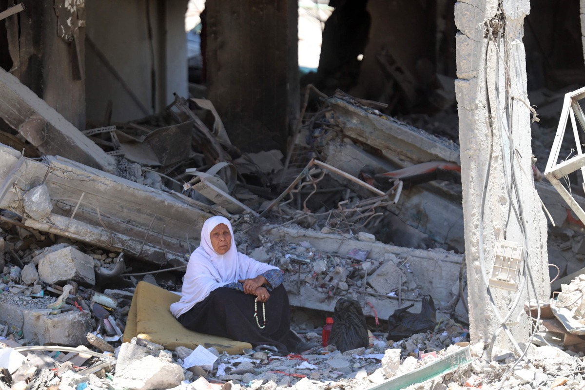 A Palestinian woman sits amid the rubble of a building in the Jabalia refugee camp in the northern gaza Strip, as she returned briefly with people who sought to check on their homes on May 31, 2024 (Photo by Omar AL-QATTAA / AFP)