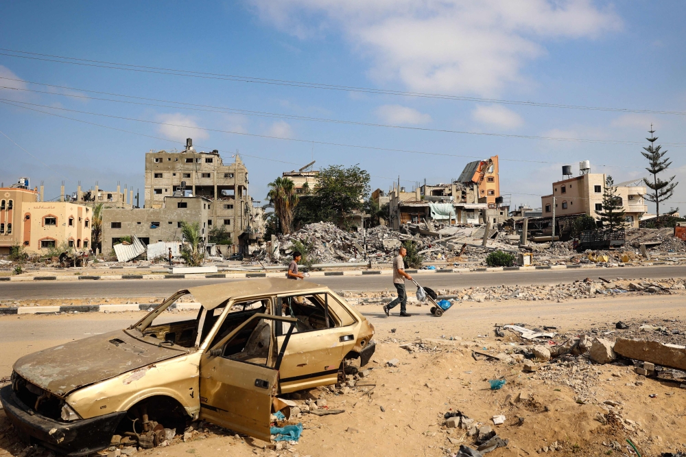 Palestinian men walk past damaged buildings after an overnight Israeli strike in al-Bureij camp in the central Gaza Strip on June 3, 2024. (Photo by Eyad Baba / AFP)