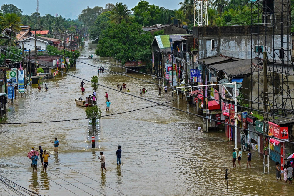 Residents wade through a flooded street after heavy rainfall in Kaduwela on the outskirts of Colombo on June 3, 2024. (Photo by Ishara S. Kodikara / AFP)

