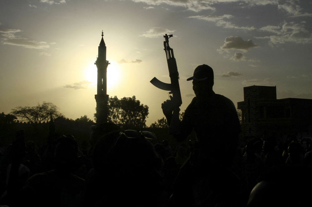 File: A fighter loyal to Sudan's army chief Abdel Fattah al-Burhan holds up a weapon backdropped by the minaret of a mosque, during a graduation ceremony in the southeastern Gedaref state on May 27, 2024. (Photo by AFP)