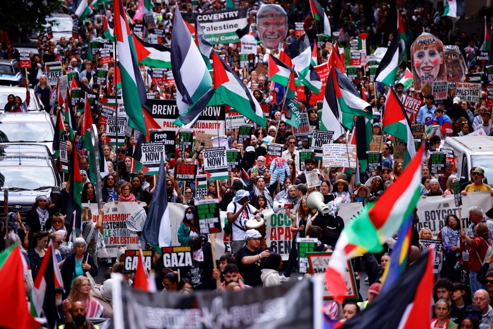 Protesters hold placards and wave Palestinian flags as they take part in a 