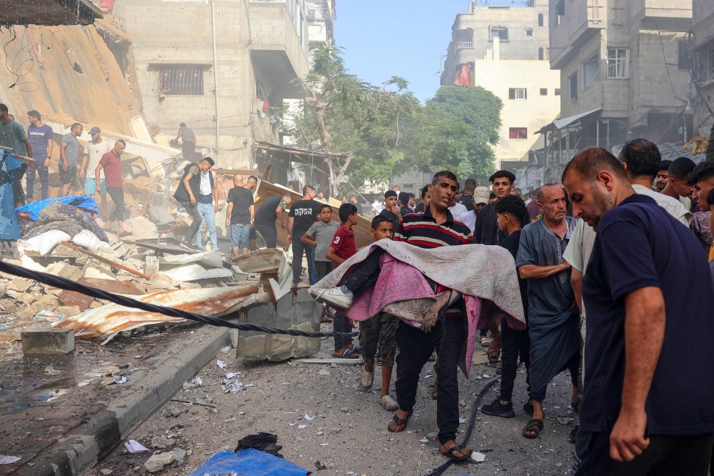 A man holds the body of a person recovered from the rubble of a building following Israeli bombardment at al-Bureij refugee camp in the central Gaza Strip on June 15, 2024. (Photo by Eyad BABA / AFP)
