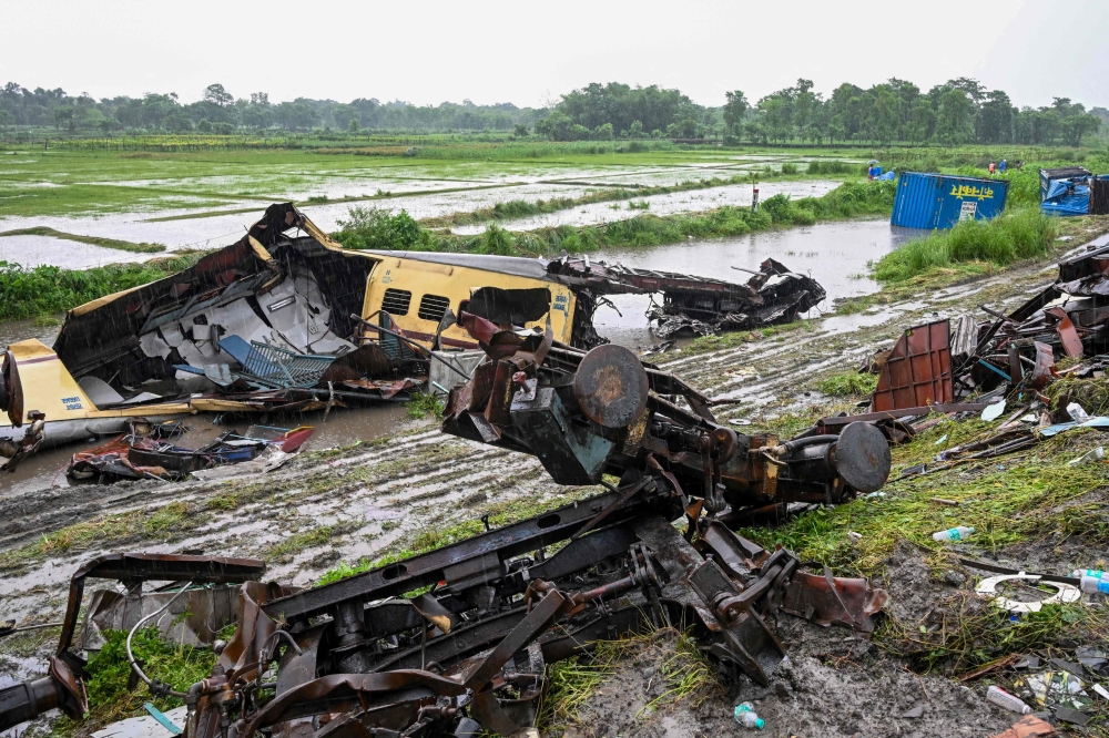Railway workers walk past the wreckage of Kanchenjunga Express passenger train at Rangapani in India's West Bengal state on June 18, 2024. (Photo by Dibyangshu Sarkar / AFP)