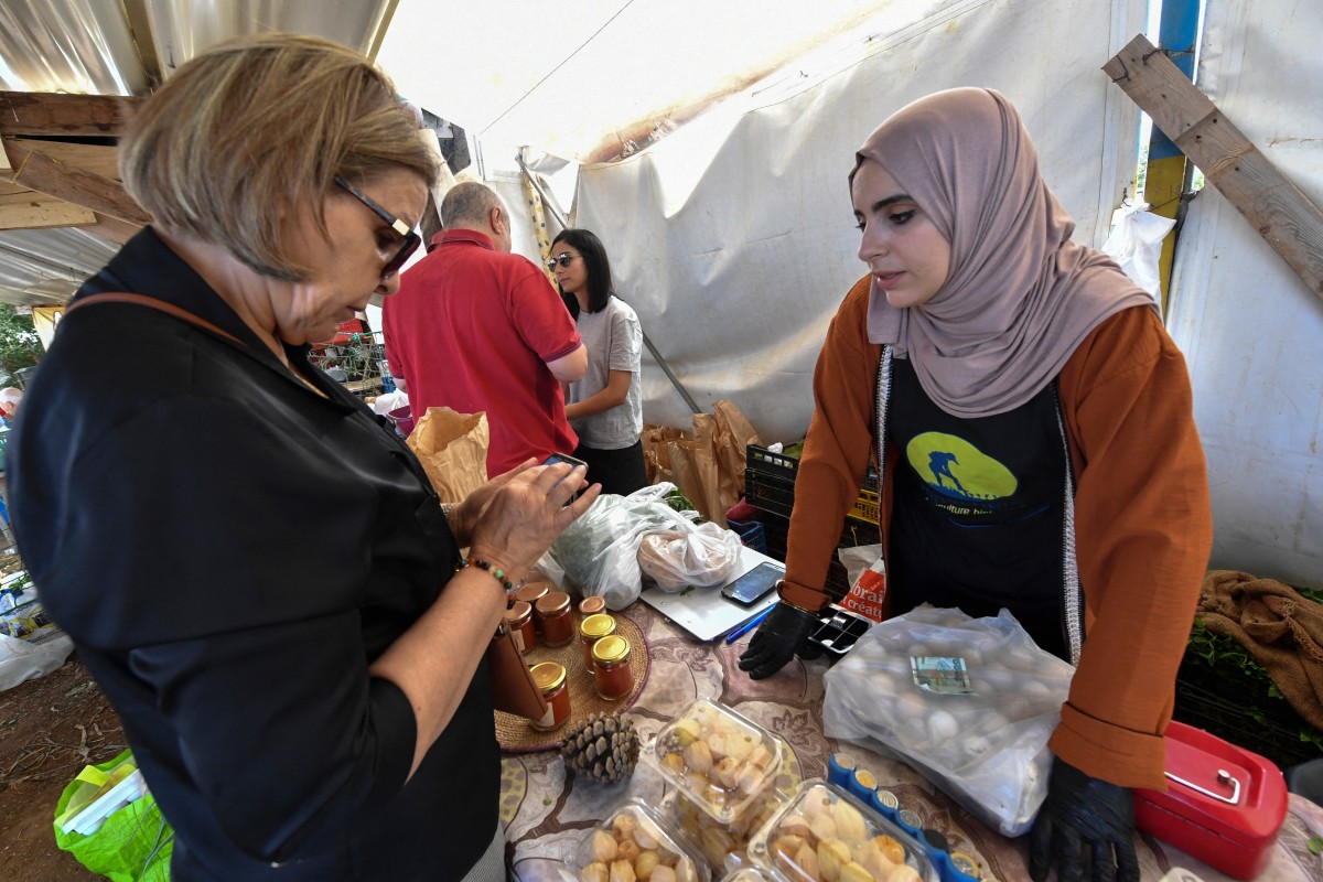 Ibtissem Mahtout (R) speaks with a customer who has come to pick up or buy their produce during the Friday market at an educational farm in Zeralda, west of Algiers on May 30, 2024. Photo by AFP.