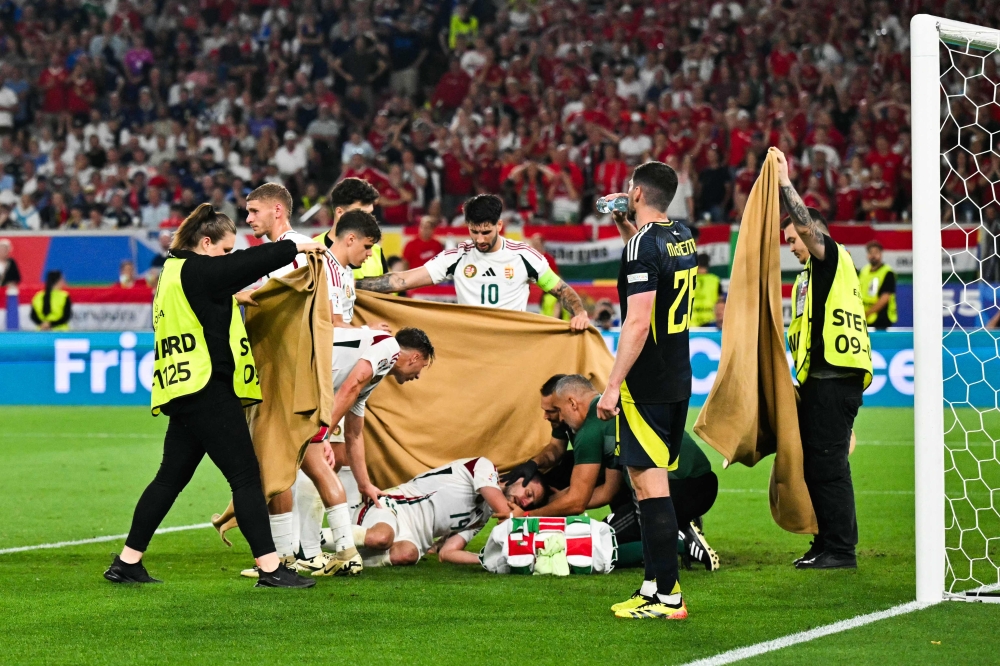 Players and stewards hold a cloth as Hungary's forward #19 Barnabas Varga (down) falls after a collision during the UEFA Euro 2024 Group A football match on June 23, 2024. (Photo by Miguel Medina / AFP)
