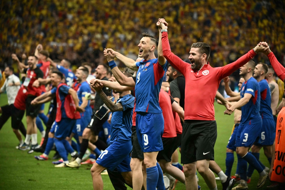Slovakia's forward #09 Robert Bozenik (centre), staff and teammates celebrate on the pitch after the UEFA Euro 2024 Group E football match between Slovakia and Romania at the Frankfurt Arena in Frankfurt am Main on June 26, 2024. (Photo by Angelos Tzortzinis / AFP)