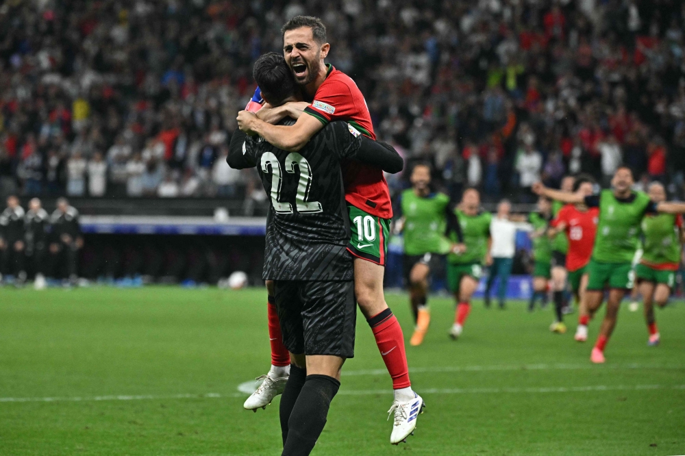 Portugal's goalkeeper #22 Diogo Costa and midfielder #10 Bernardo Silva celebrate their win at the end of the UEFA Euro 2024 round of 16 football match between Portugal and Slovenia at the Frankfurt Arena in Frankfurt am Main on July 1, 2024. (Photo by JAVIER SORIANO / AFP)
