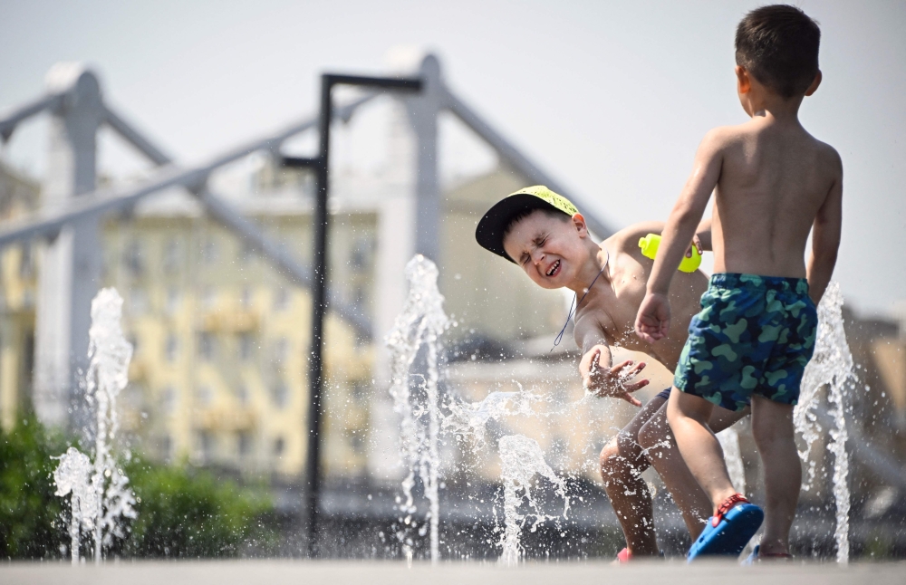 Children play in a fountain during a midday heat in central Moscow on July 3, 2024. (Photo by Alexander NEMENOV / AFP)
