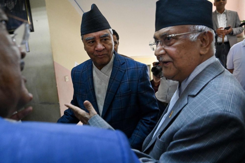 Former prime minister or Nepali Congress president Sher Bahadur Deuba (centre) talks with Communist Party Nepal-Union Marxist Leninist (CPN-UML) chairman KP Sharma Oli (R) as he arrives to attend the photo exhibition of late former PM Girja Prasad Koirala in Kathmandu on July 2, 2024. (Photo by Prakash Mathema / AFP)