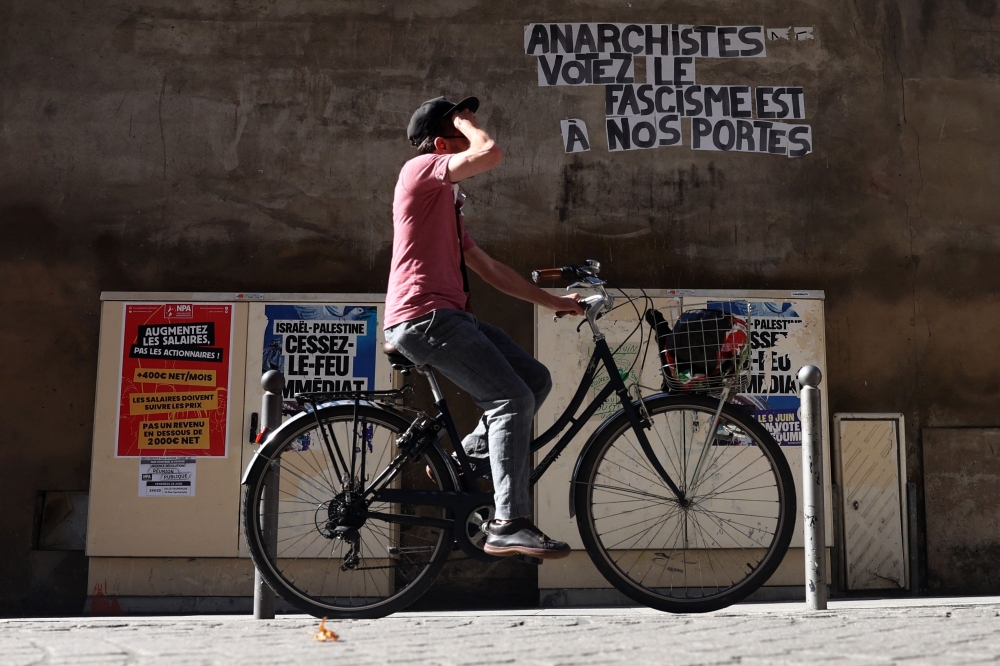A cylist rides past placards reading 