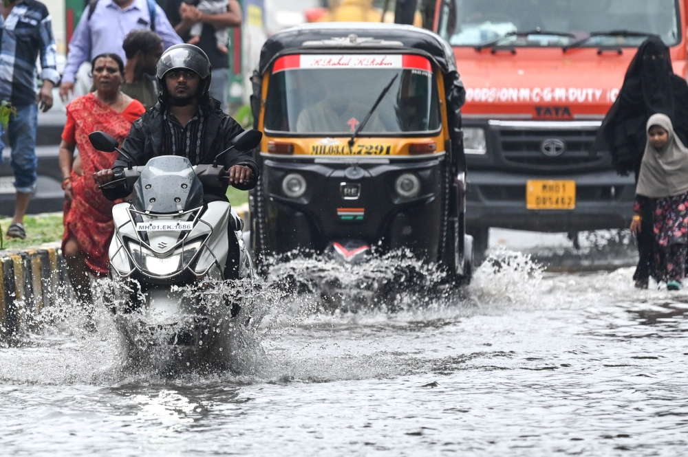 Vehicles drive through a flooded street after rain showers in Mumbai on July 8, 2024. (Photo by Punit Paranjpe / AFP)
 