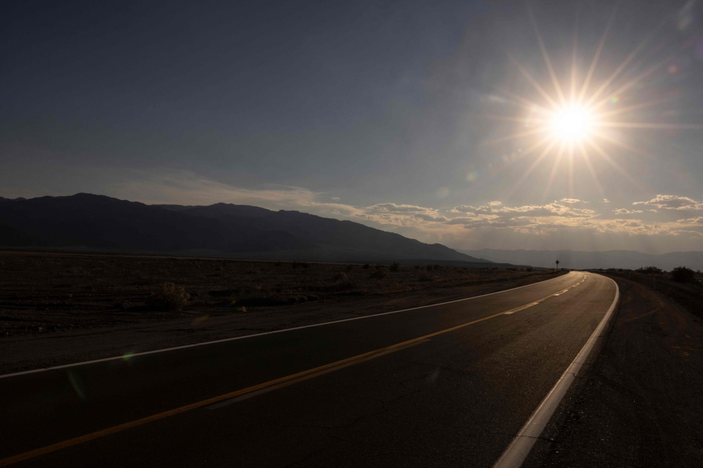 The sun sets over California Highway 190 winding across Death Valley National Park, near Furnace Creek, during a heatwave impacting Southern California on July 7, 2024. (Photo by ETIENNE LAURENT / AFP)
