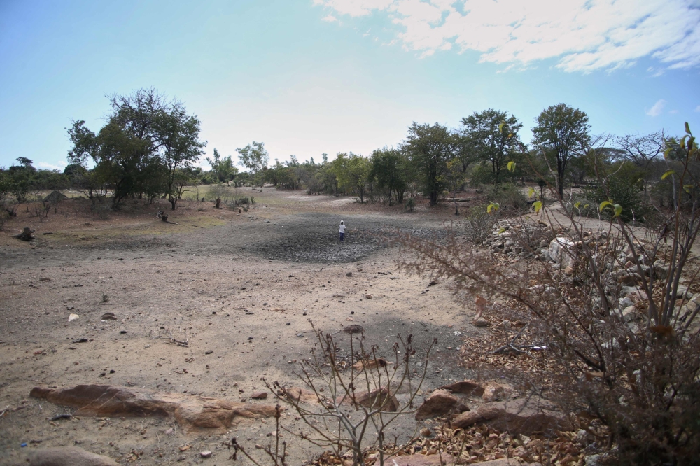 Farmer Takesure Chimbu walks on the dry bed of the Kapotesa dam in Mudzi on July 2, 2024. (Photo by Jekesai Njikizana / AFP)