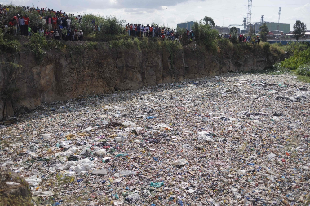 People stand on the edge of a dumpsite where six bodies were found at the landfill in Mukuru slum, Nairobi, on July 12, 2024. (Photo by Simon Maina / AFP) 