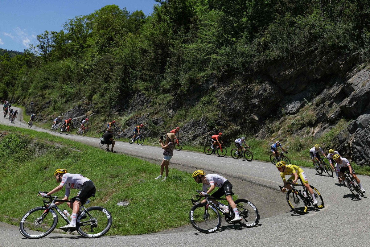 UAE Team Emirates team's Slovenian rider Tadej Pogacar wearing the overall leader's yellow jersey cycles with the pack of riders (peloton) during the 15th stage of the 111th edition of the Tour de France cycling race, 197,7 km between Loudenvielle and Plateau de Beille, in the Pyrenees mountains, southwestern France, on July 14, 2024. (Photo by Thomas SAMSON / AFP)
