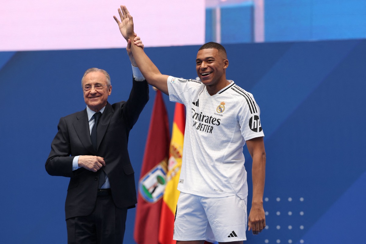 French forward Kylian Mbappe (R) waves to the fans next to Real Madrid's President Florentino Perez during a first appearance as a Real Madrid player at the Santiago Bernabeu Stadium in Madrid on July 16, 2024.  (Photo by Pierre-Philippe MARCOU / AFP)
