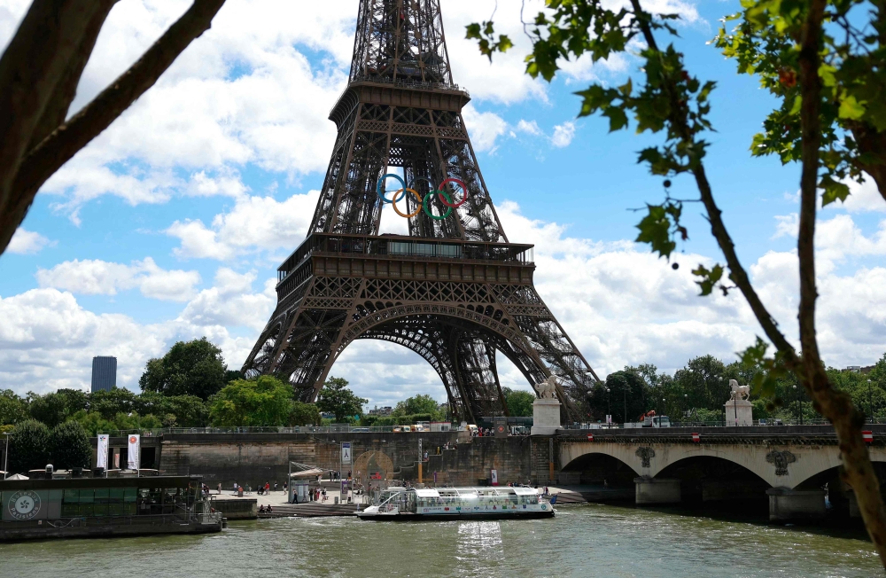 A Seine river bus boat docks in front the Eiffel Tower adorned with Olympic rings ahead of the Paris 2024 Olympic and Paralympic Games in Paris in July 16, 2024 (Photo by EMMANUEL DUNAND / AFP)
