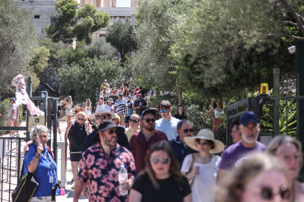 Tourists leave the Acropolis hill in Athens on July 17, 2024. (Photo by Aris Oikonomou / AFP)
 