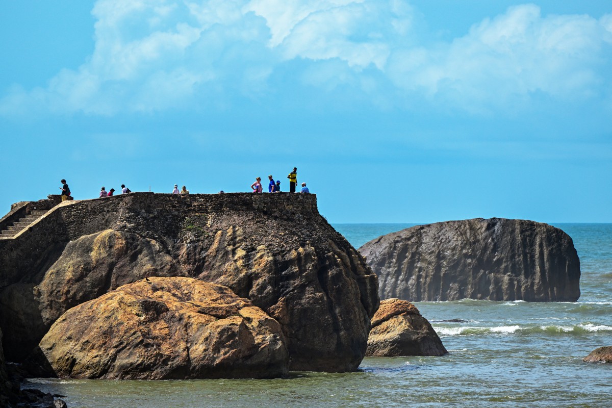 Tourists climb a rock at Galle Fort in Galle on July 15, 2024. (Photo by Ishara S. KODIKARA / AFP)
