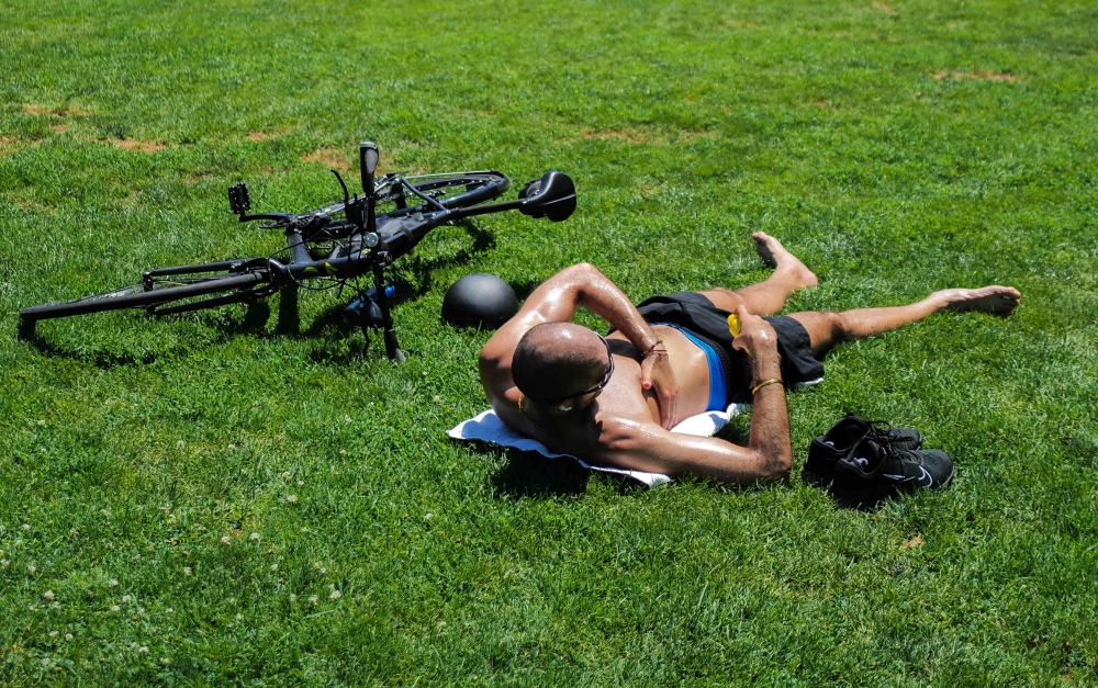 A man applies sunscreen as he sunbathes in Central Park in the Manhattan borough of New York on July 11, 2024. Photo by Charly TRIBALLEAU / AFP