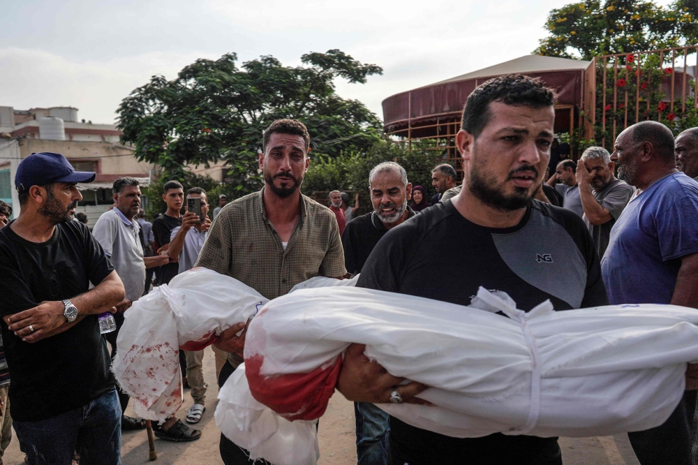 Mourners carry the bodies of members of the Qadih family to a burial ground in Khuzaa in the southern Gaza Strip, following an overnight Israeli strike that hit their house in Bani Suheila, reportedly killing two children, their father, uncle, paternal grandparents and severely injuring their mother, on July 21, 2024. (Photo by Bashar TALEB / AFP)
