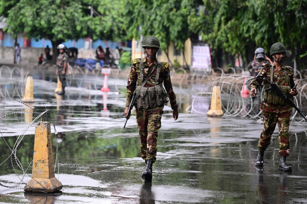 Bangladesh army personnel keep a vigil near barbed wire barricades amid a curfew following clashes between police and protestors, in Dhaka on July 22, 2024. (Photo by Munir Uz Zaman / AFP)