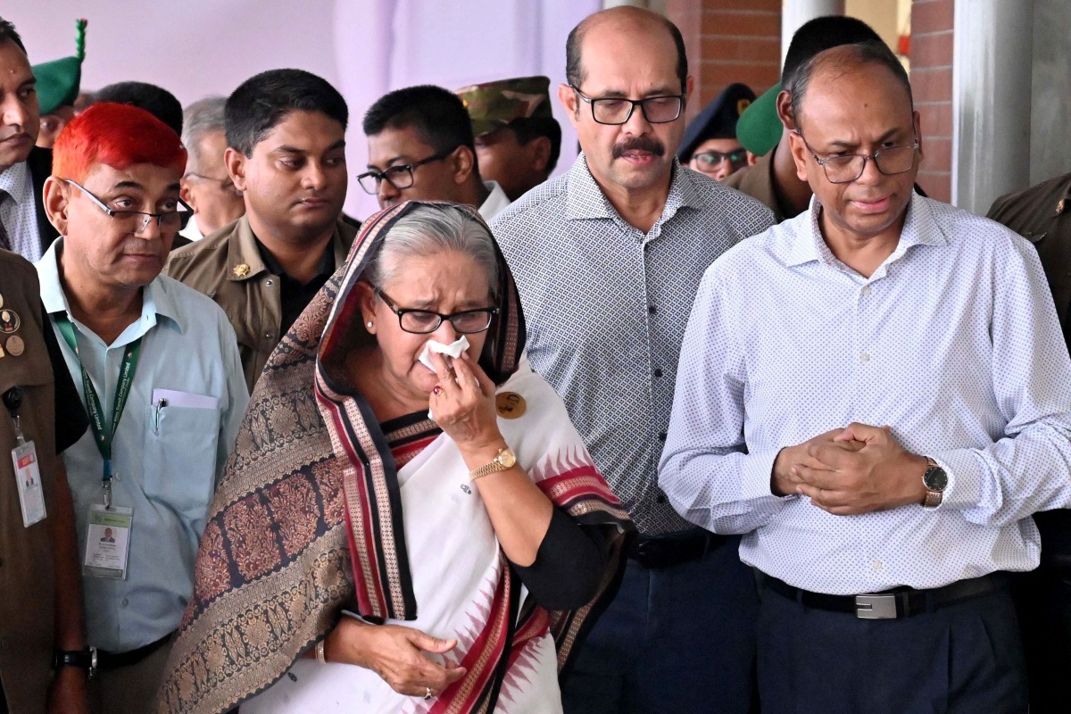 In this handout photograph taken and released on July 25, 2024 by Bangladesh Prime Minister's Office, Prime Minister Sheikh Hasina (C) weeps while she visits a metro station in Mirpur vandalized by students during the anti-quota protests. 