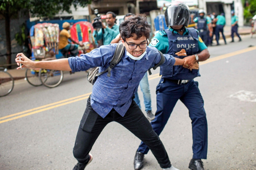 A Bangladesh police personnel detains a student during a rally against quotas in government jobs, along the street in Dhaka on July 29, 2024. (Photo by Abu Sufian Jewel / AFP)