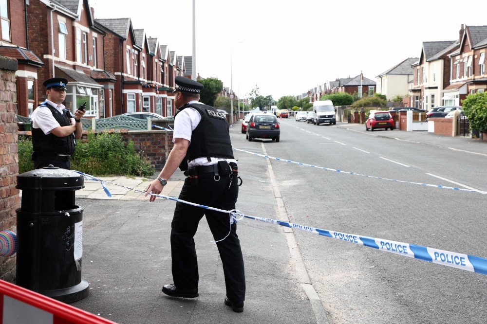 Police officers stand guard behind a cordon on Hart Street in Southport, northwest England, on July 29, 2024, following a knife attack. (Photo by Darren Staples / AFP)
