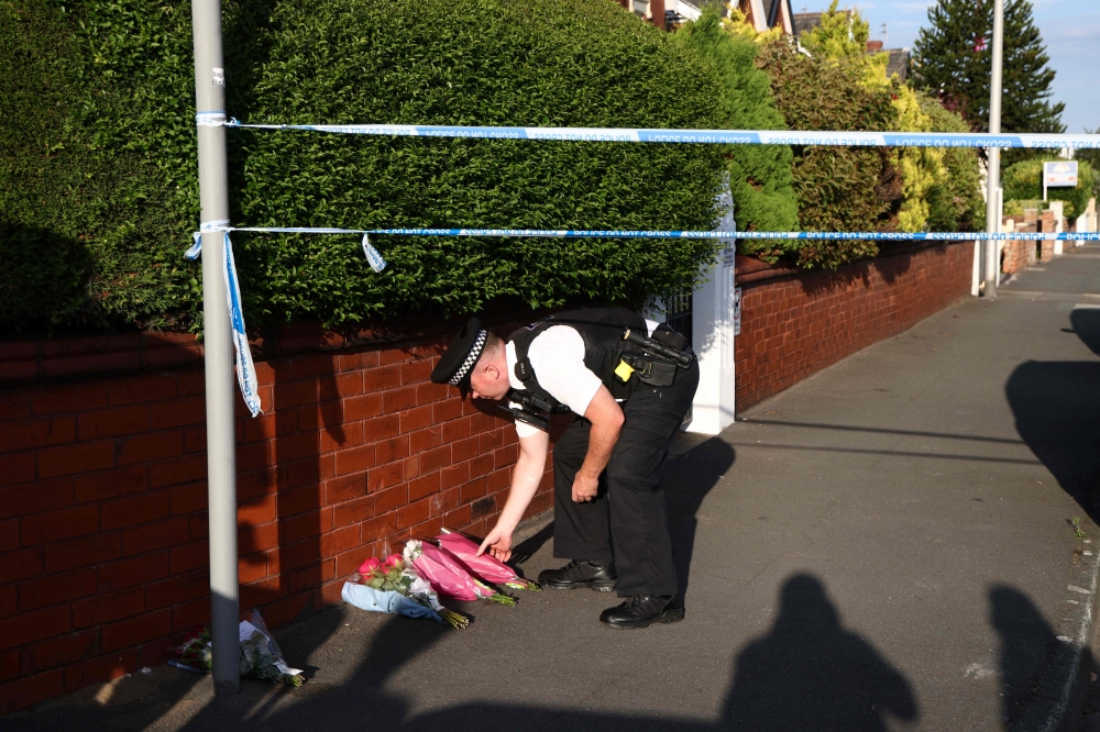 A police officer lays floral tributes brought by wellwishers on Hart Street in Southport, northwest England, on July 29, 2024, following a knife attack. (Photo by Darren Staples / AFP)