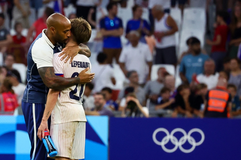 France's coach Thierry Henry (L) hugs France's midfielder #21 Johann Lepenant at the end of the Paris 2024 Olympic Games men's group A football match between New Zealand and France, at the Marseille Stadium, in Marseille, southern France, on July 30, 2024. (Photo by Clement MAHOUDEAU / AFP)
