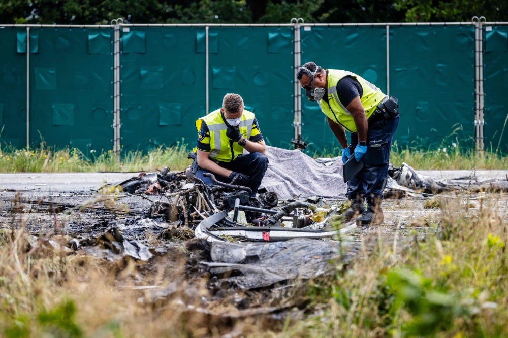 Dutch Police officers investigate the debris of a small plane after it crashed on the A58 motorway in Rucphen on July 31, 2024. Photo by Jeffrey GROENEWEG / ANP / AFP