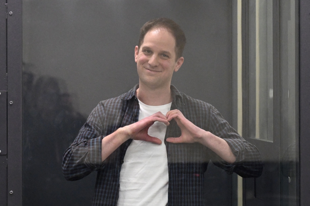 File: US journalist Evan Gershkovich, arrested on espionage charges, shapes a heart with his hands inside a defendants' cage after a hearing to consider an appeal on his extended pre-trial detention, at the The first court of appeal in Moscow on April 23, 2024. (Photo by Natalia Kolesnikova / AFP)