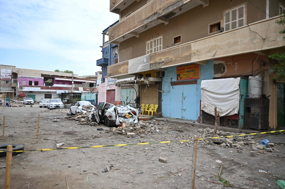 Damaged cars lie in a street in Port Sudan after torrential rains on August 1, 2024. (Photo by AFP)