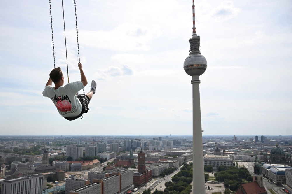 Pascal Vent sways 120m above the rooftops of Berlin, from Europe's highest swing at Alexanderplatz, on July 31, 2024. (Photo by RALF HIRSCHBERGER / AFP)