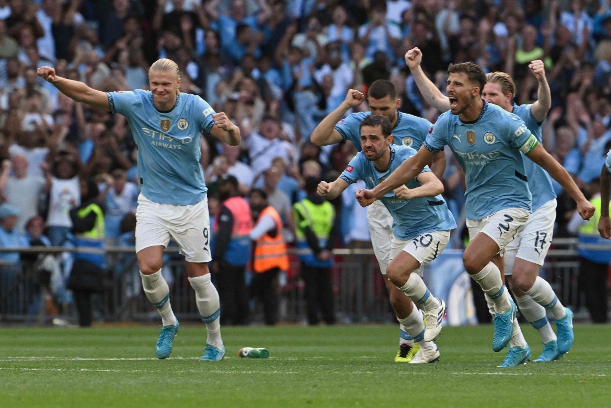 Manchester City's Portuguese defender #03 Ruben Dias (R) and Manchester City's Portuguese midfielder #20 Bernardo Silva (C) celebrate after Manchester City's Swiss defender #25 Manuel Akanji scored the winning goal during a penalty shoot out in the English FA Community Shield football match between Manchester City and Manchester United at Wembley Stadium, in London on August 10, 2024. (Photo by JUSTIN TALLIS / AFP) 
