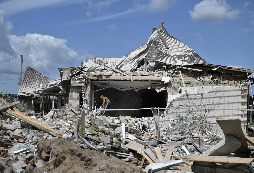A local resident clears debris in a residential house, heavily damaged following a Russian missile strike on August 11, 2024, in a village in the Brovary district, Kyiv region, amid the Russian invasion of Ukraine. (Photo by Genya Savilov / AFP)
