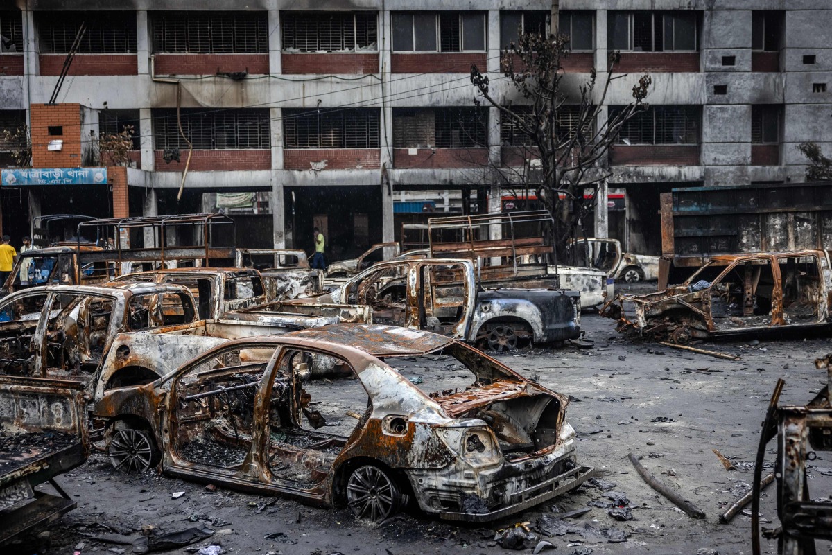 Police vehicles that were burned during anti-government demonstrations are seen inside the compound of a police station as students volunteering to maintain law and order are in control of the Jatrabari Police Station in Dhaka on August 11, 2024. Nobel laureate Muhammad Yunus and his newly named interim government set out on August 9 to restore 