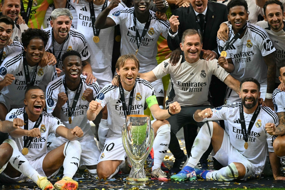 Real Madrid's player celebrate with the trophy after the UEFA Super Cup football match between Real Madrid and Atalanta BC in Warsaw, on August 14, 2024. (Photo by Sergei GAPON / AFP)
