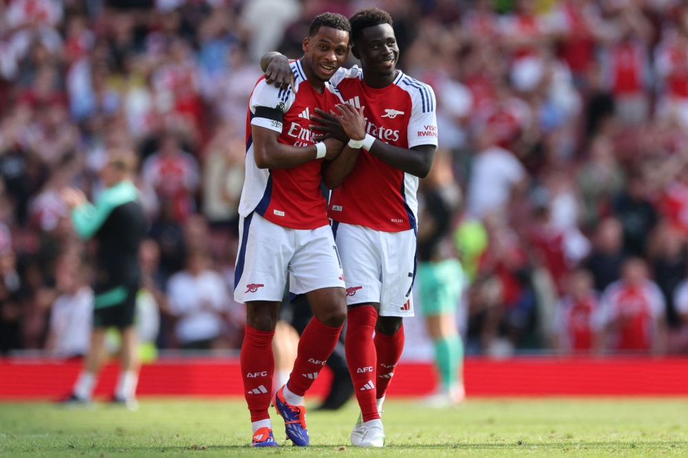 Arsenal's Dutch defender #12 Jurrien Timber (L) and Arsenal's English midfielder #07 Bukayo Saka (R) celebrate their win on the pitch after the English Premier League football match between Arsenal and Wolverhampton Wanderers at the Emirates Stadium in London on August 17, 2024. (Photo by Adrian DENNIS / AFP)
