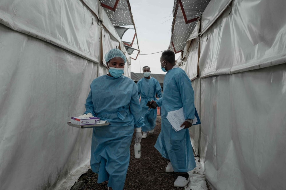 Health workers walk between wards at the Mpox treatment centre at Nyiragongo General Referral Hospital, north of Goma on August 17, 2024. (Photo by GUERCHOM NDEBO / AFP)
