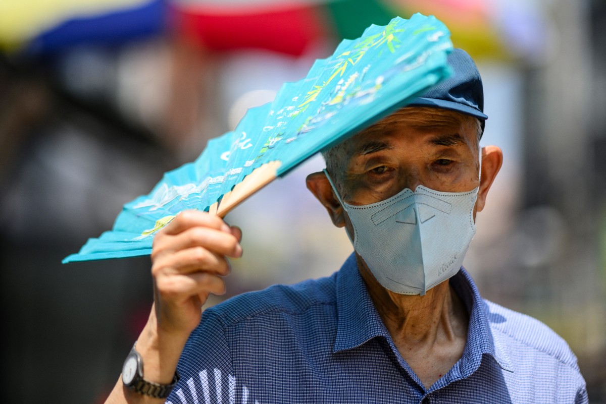 A man uses his fan to shade himself from the sun in Seoul on August 16, 2024, during a prolonged heatwave which has gripped much of the country. (Photo by ANTHONY WALLACE / AFP)