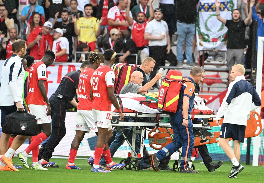 Rennes' players walk next to Lille's English forward Angel Gomes evacuated on a stretcher off the pitch after being injured during the French L1 football match between Stade de Reims and Lille LOSC at the Stade Auguste-Delaune in Reims, northern France, on August 17, 2024. (Photo by FRANCOIS NASCIMBENI / AFP)
