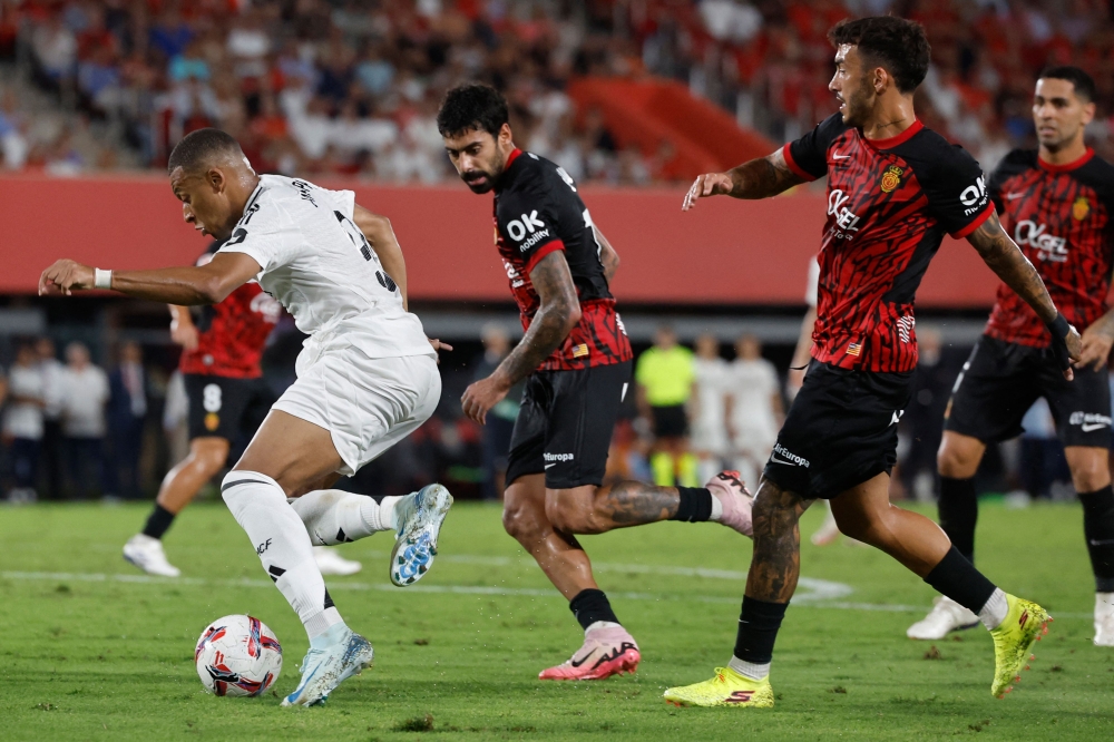 Real Madrid's French forward #09 Kylian Mbappe (L) dribbles the ball as he is challenged by Real Mallorca's Spanish midfielder #18 Antonio Sanchez (2R) during the Spanish league football match between RCD Mallorca and Real Madrid CF at the Mallorca Son Moix stadium in Palma de Mallorca on August 18, 2024. (Photo by OSCAR DEL POZO / AFP)
