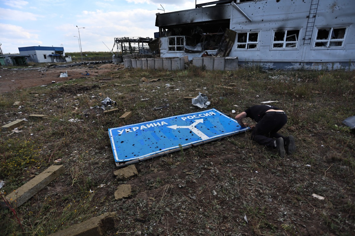 This photograph taken on 16 August, 2024, during a media tour organised by Ukraine, shows a man examining a damaged road sign.
