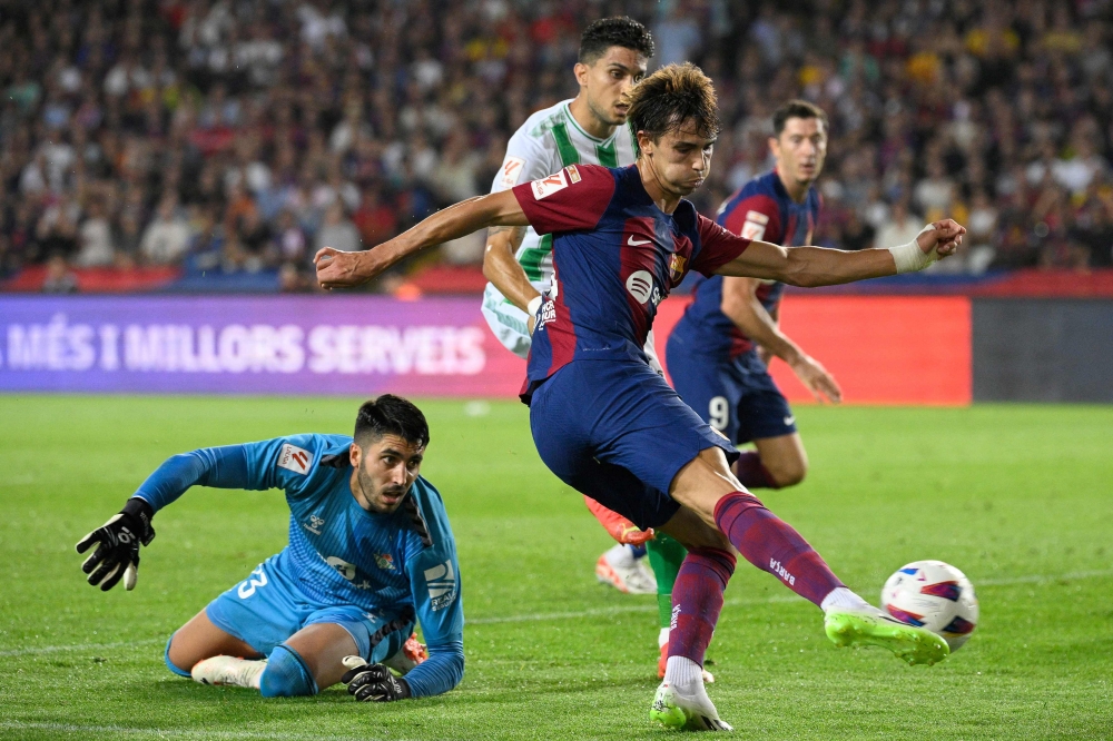 Barcelona's Portuguese forward #14 Joao Felix kicks the ball and scores his team's first goal during the Spanish Liga football match between FC Barcelona and Real Betis at the Estadi Olimpic Lluis Companys in Barcelona on September 16, 2023. (Photo by Josep LAGO / AFP)

