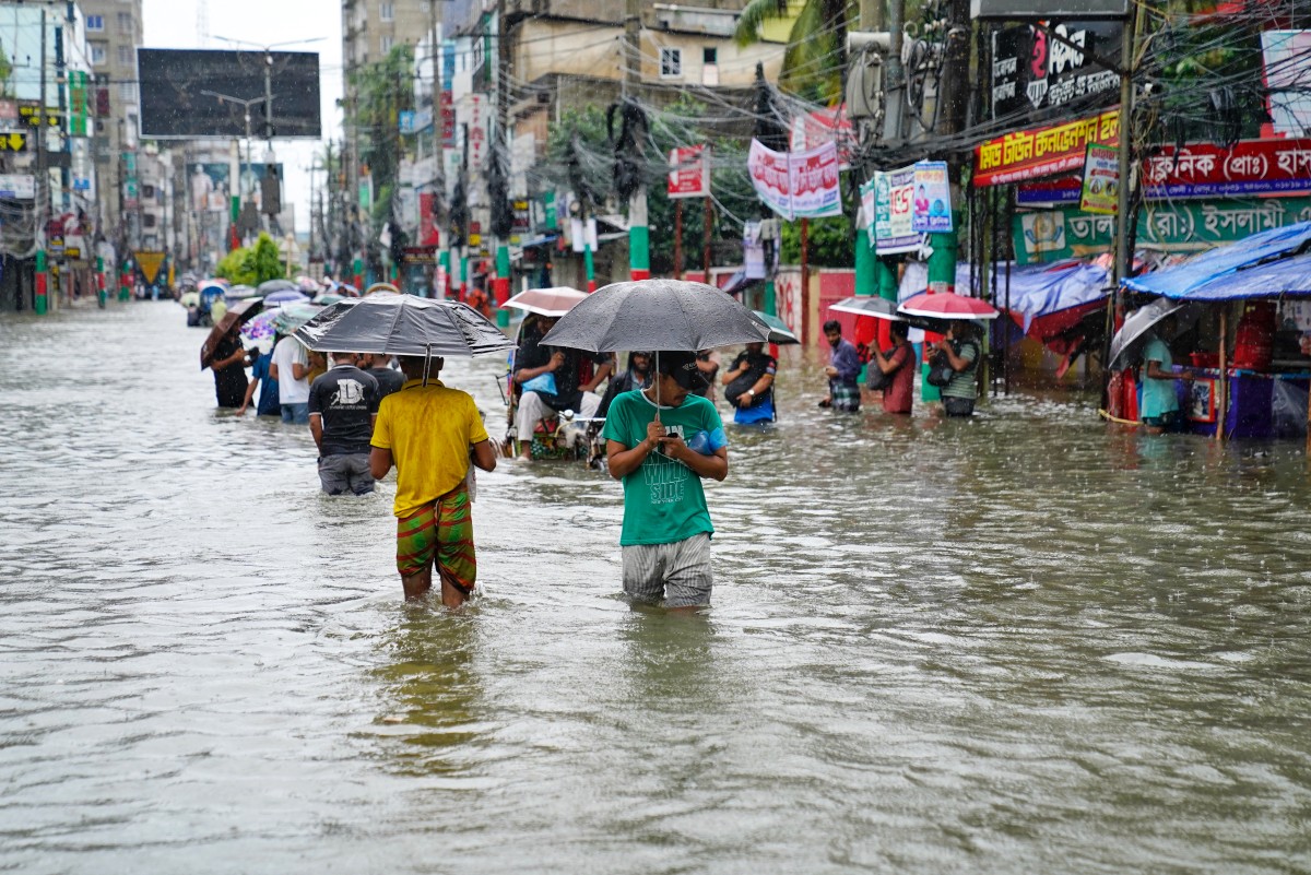 People carrying umbrellas, wade through a flooded street amid rainfall in Feni on August 22, 2024. (Photo by AFP)
