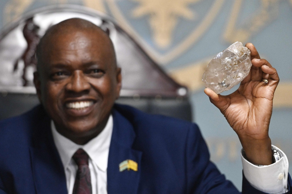 Botswana's President Mokgweetsi Masisi holds a large diamond discovered in Botswana at his office in Gaborone on August 22, 2024. (Photo by Monirul Bhuiyan / AFP)

